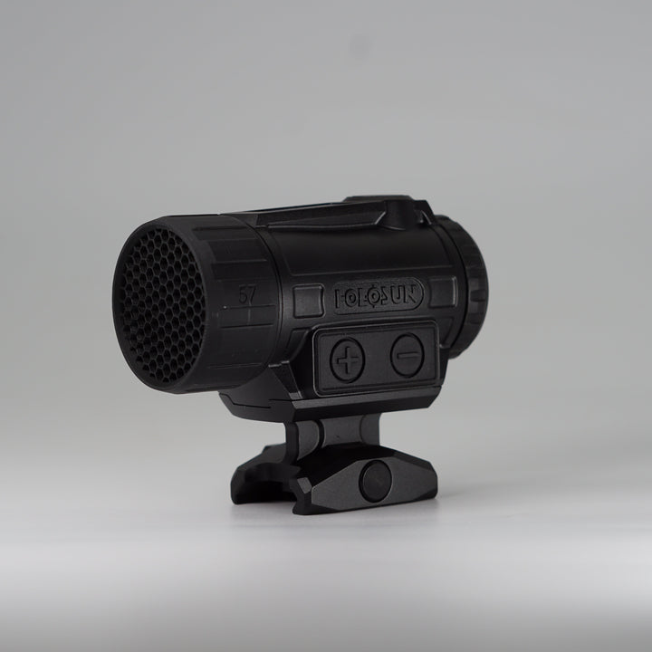 A black tactical-style ARD device with a cylindrical body, perforated front hex pattern, on a holosun red dot optic and mounting base, photographed on a smooth light gray studio background. 